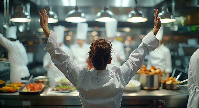 Chef qui lève les mains à la fin de la préparation d'un plat de concours