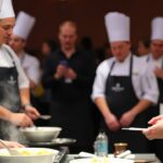 Chef préparant un plat devant un jury de concours